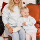 Woman and child sitting together in a festive setting with Christmas decorations.
