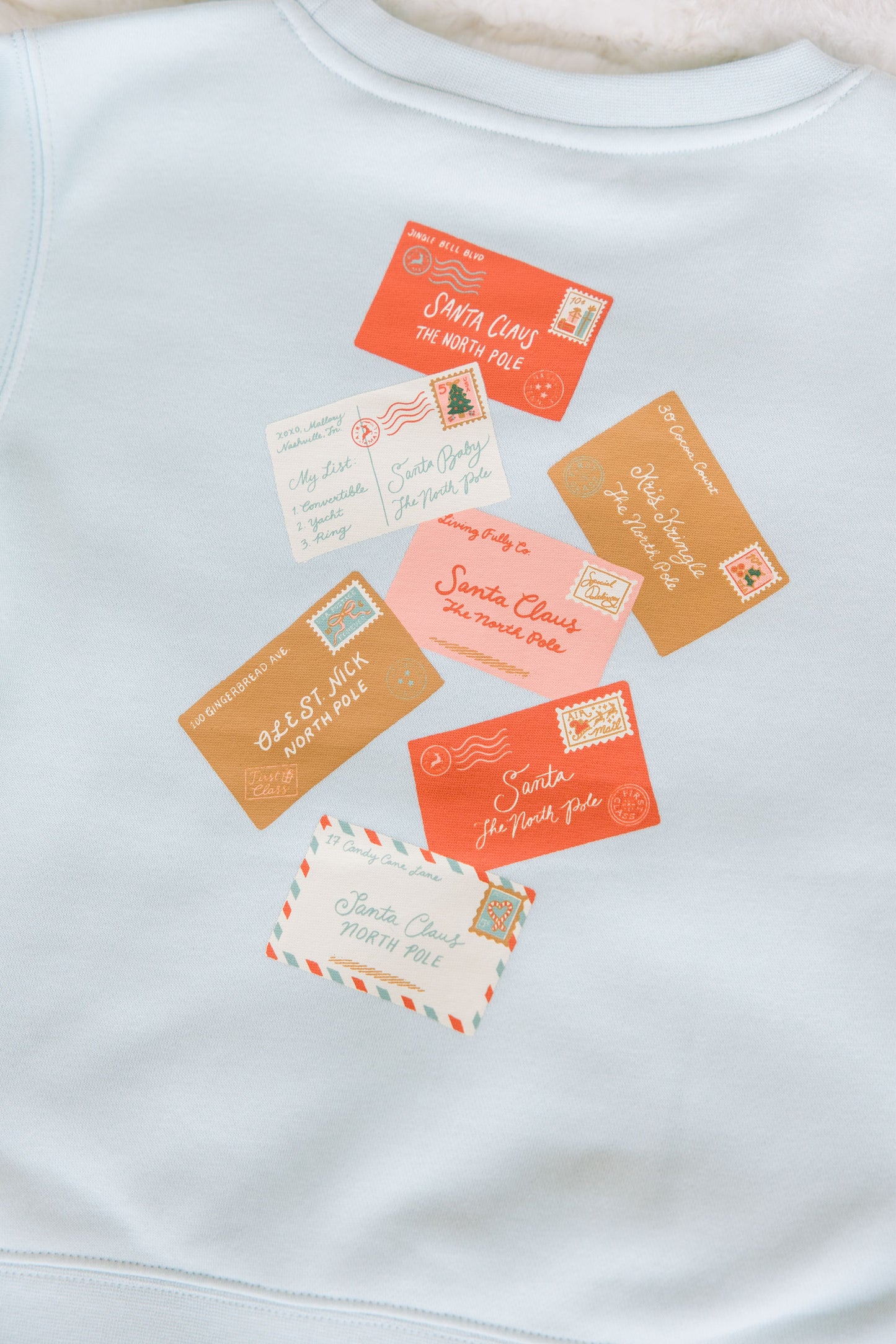 Light blue sweatshirt with colorful vintage-style postcards printed on it