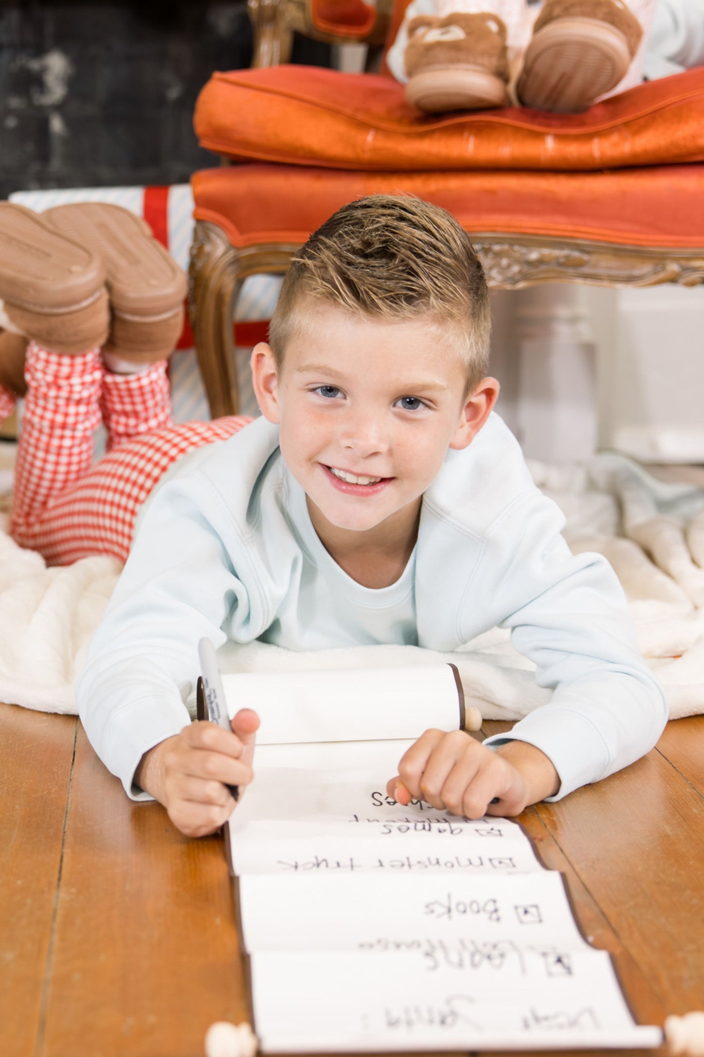 Young boy lying on the ground with a piece of paper, smiling.