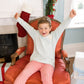 Child sitting in a red chair with Christmas decorations in the background