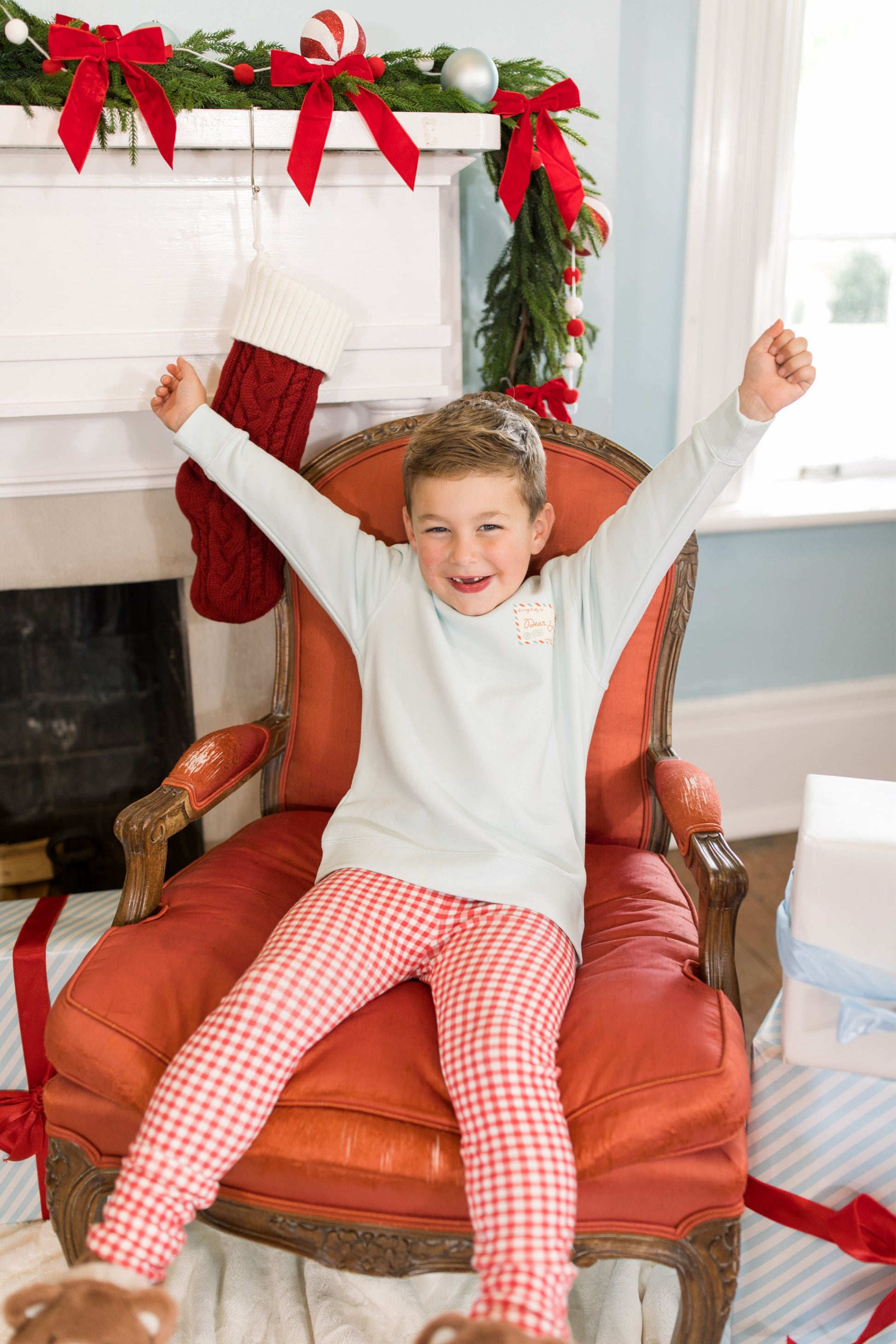Child sitting in a red chair with Christmas decorations in the background