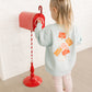 Child interacting with a red mailbox against a white wall