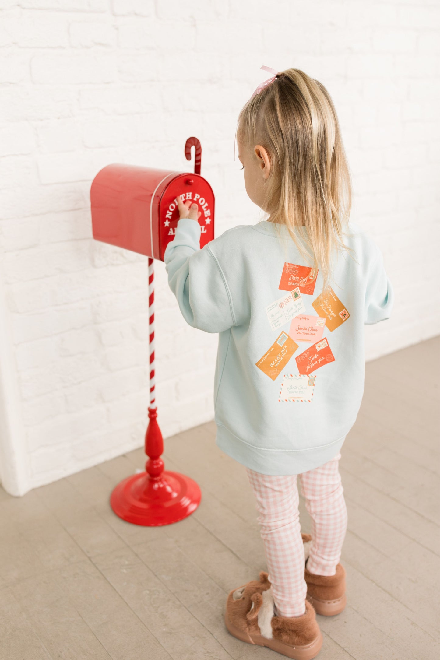 Child interacting with a red mailbox against a white wall