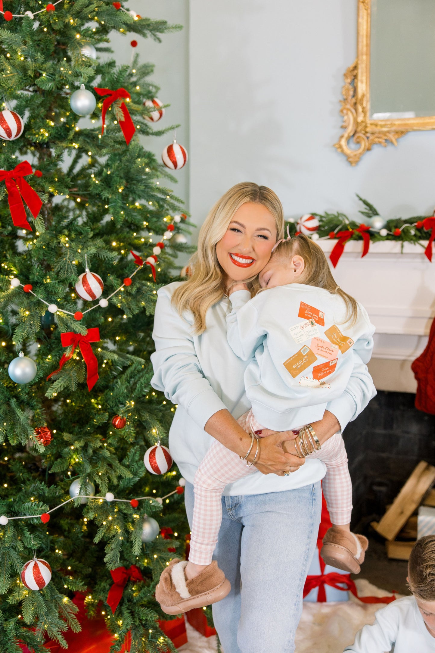 Woman holding a child in front of a decorated Christmas tree