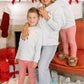 Woman and two children in matching outfits in a festive living room with Christmas decorations.