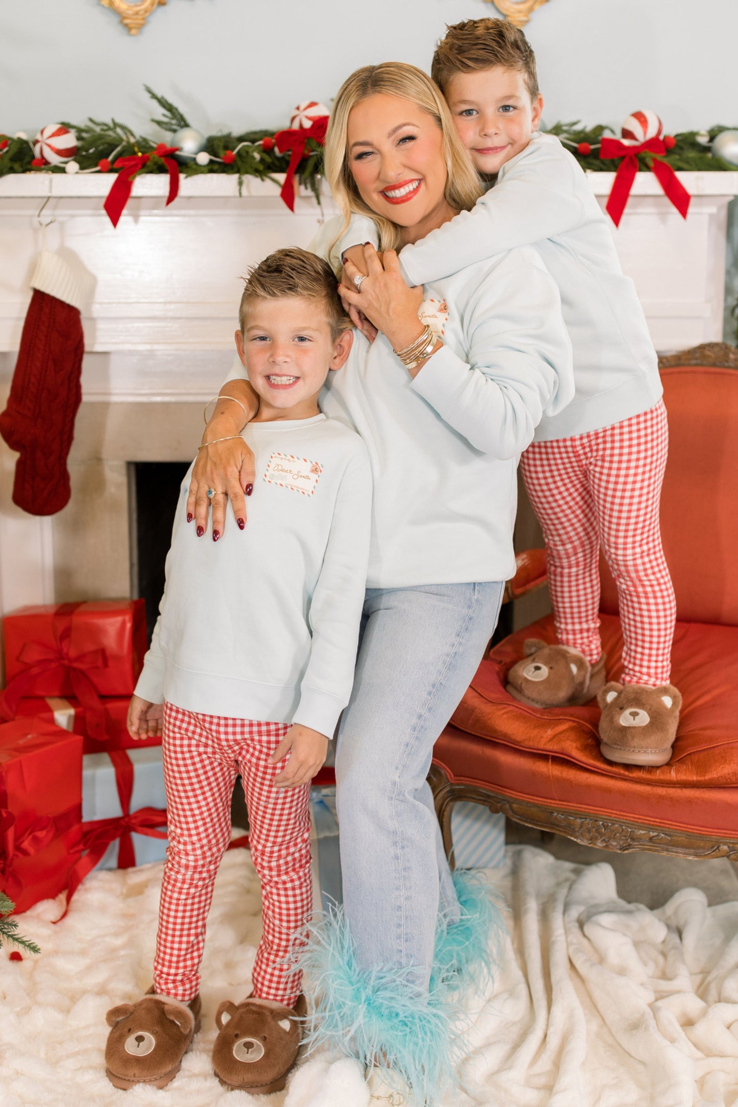 Woman and two children in matching outfits in a festive living room with Christmas decorations.