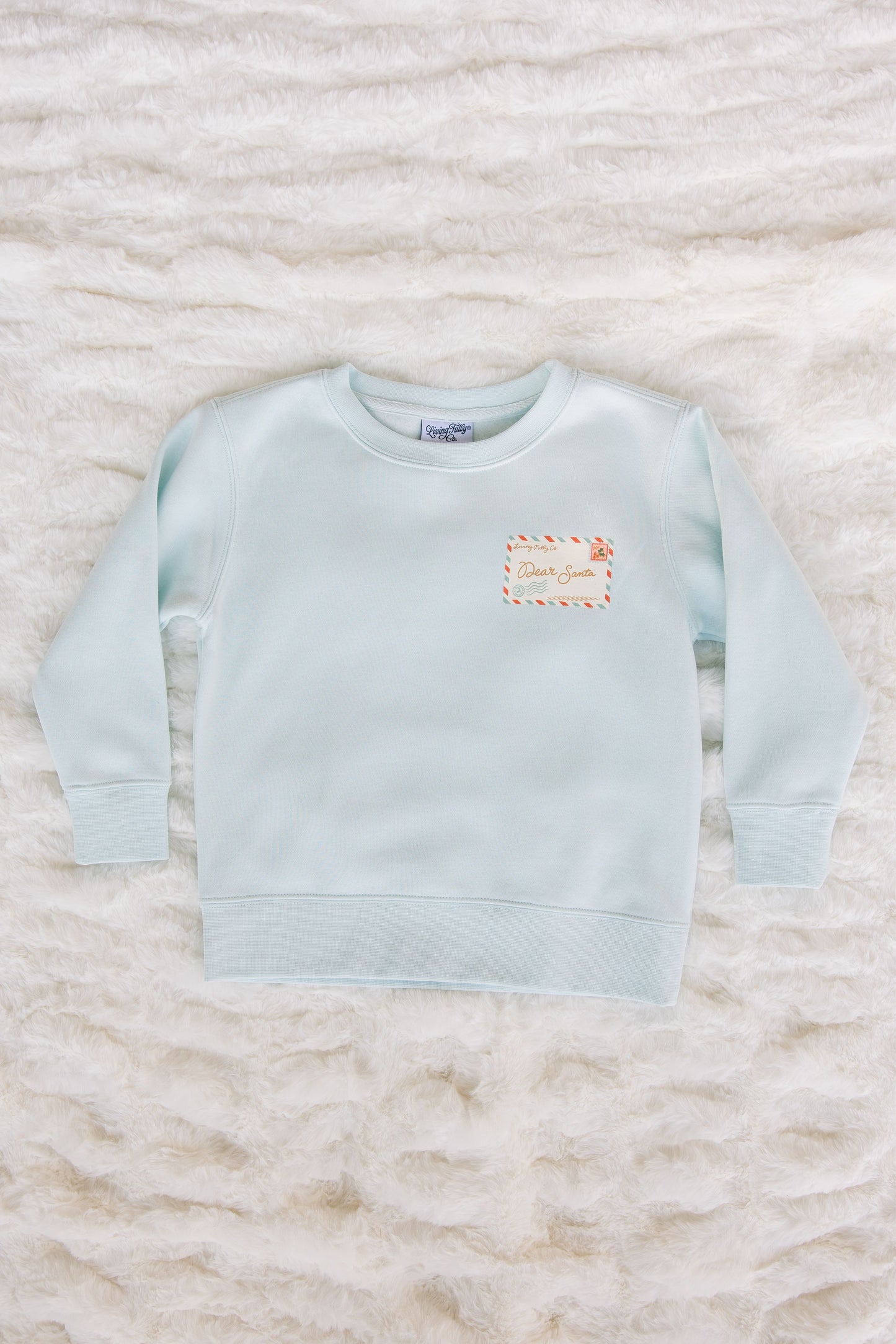 Light blue sweatshirt with a small logo on a textured white surface