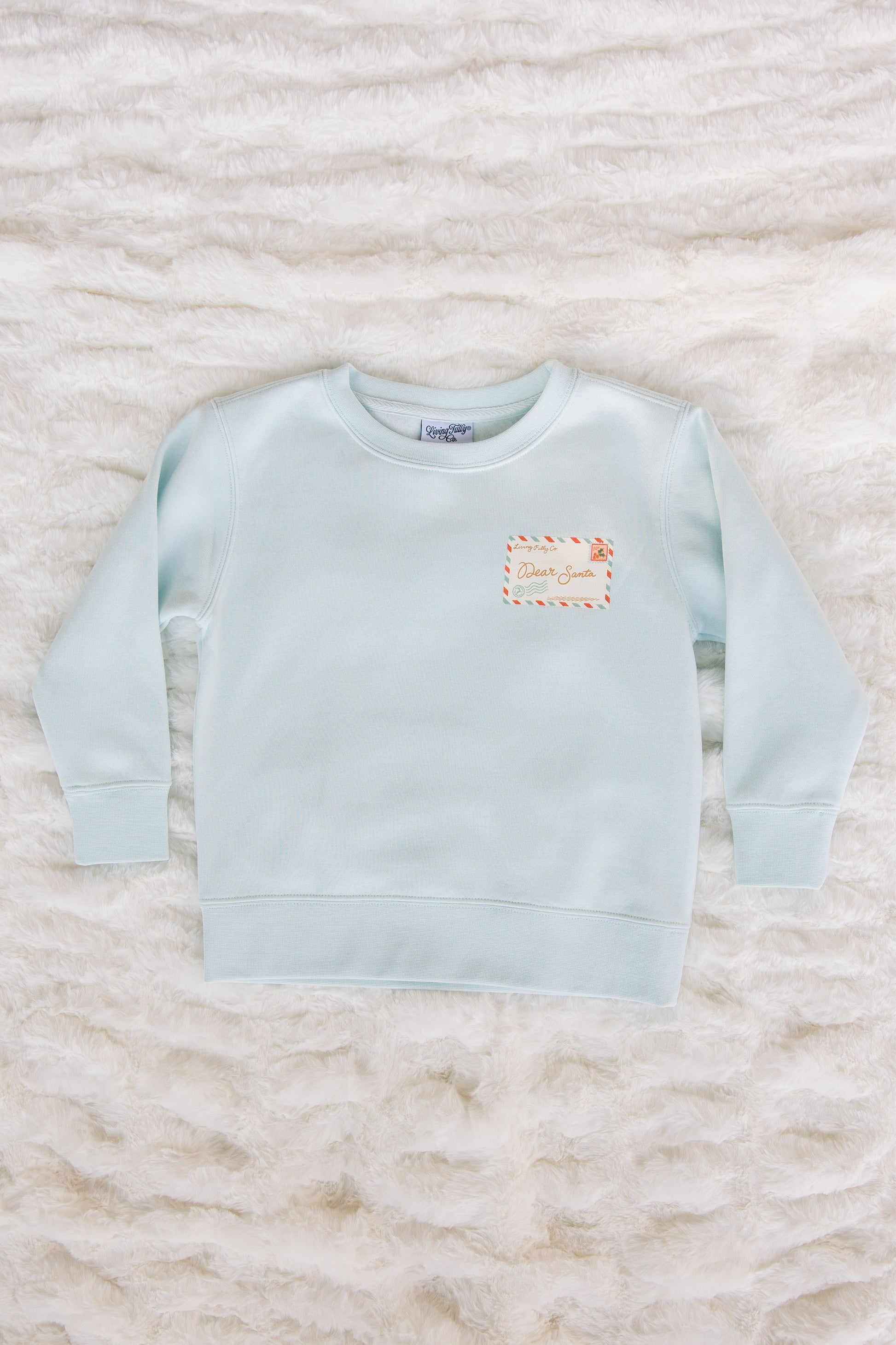 Light blue sweatshirt with a small logo on a textured white surface