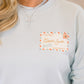 Light blue sweatshirt with a 'Dear Santa' postcard printed patch worn by a person.