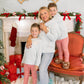 Woman and two children in front of a decorated fireplace with Christmas decorations.