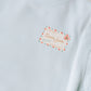 Light blue sweatshirt with a decorative label on a textured surface