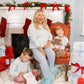 Woman and two children in a festive living room with Christmas decorations and presents.