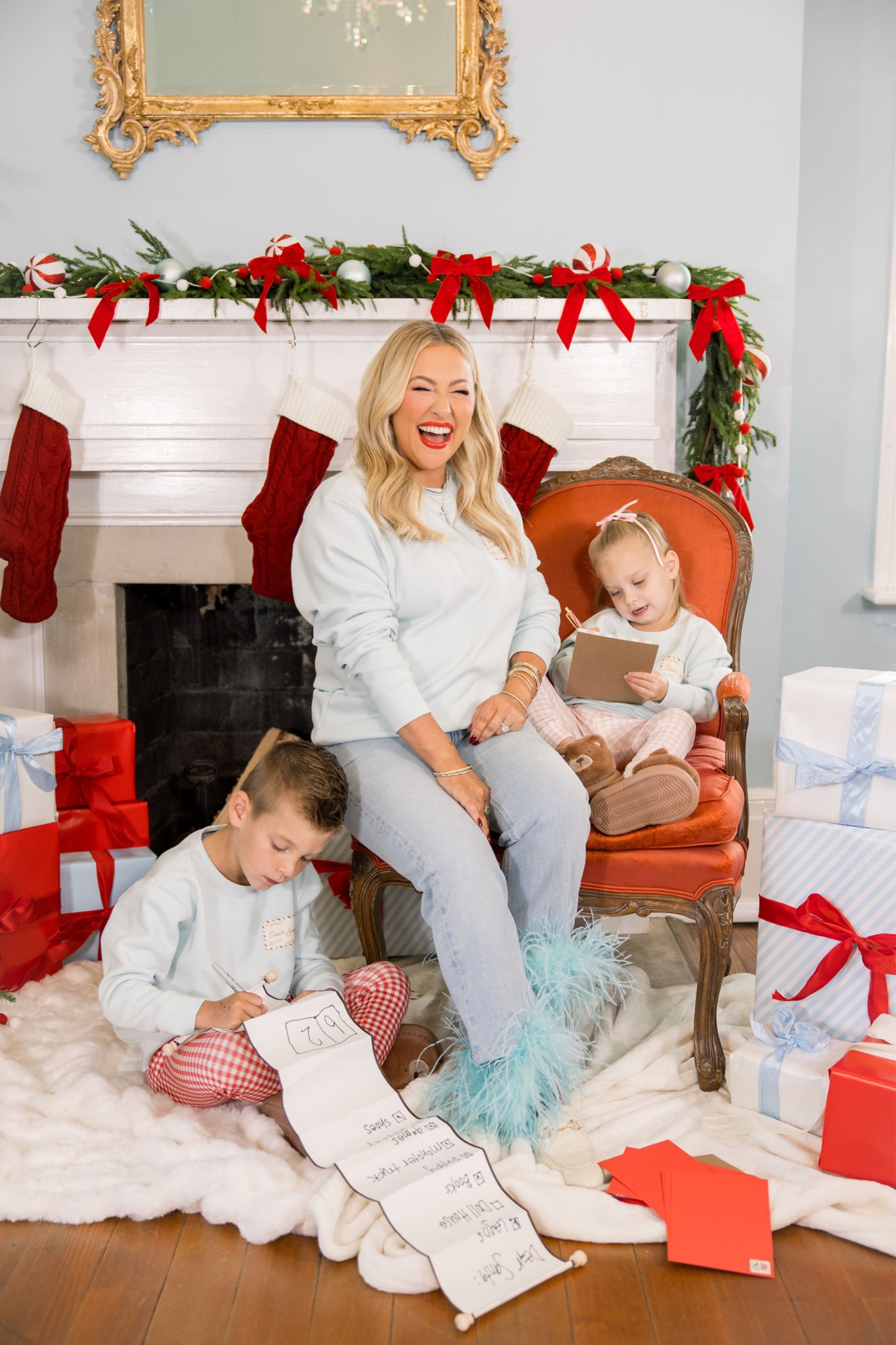 Woman and two children in a festive living room with Christmas decorations and presents.