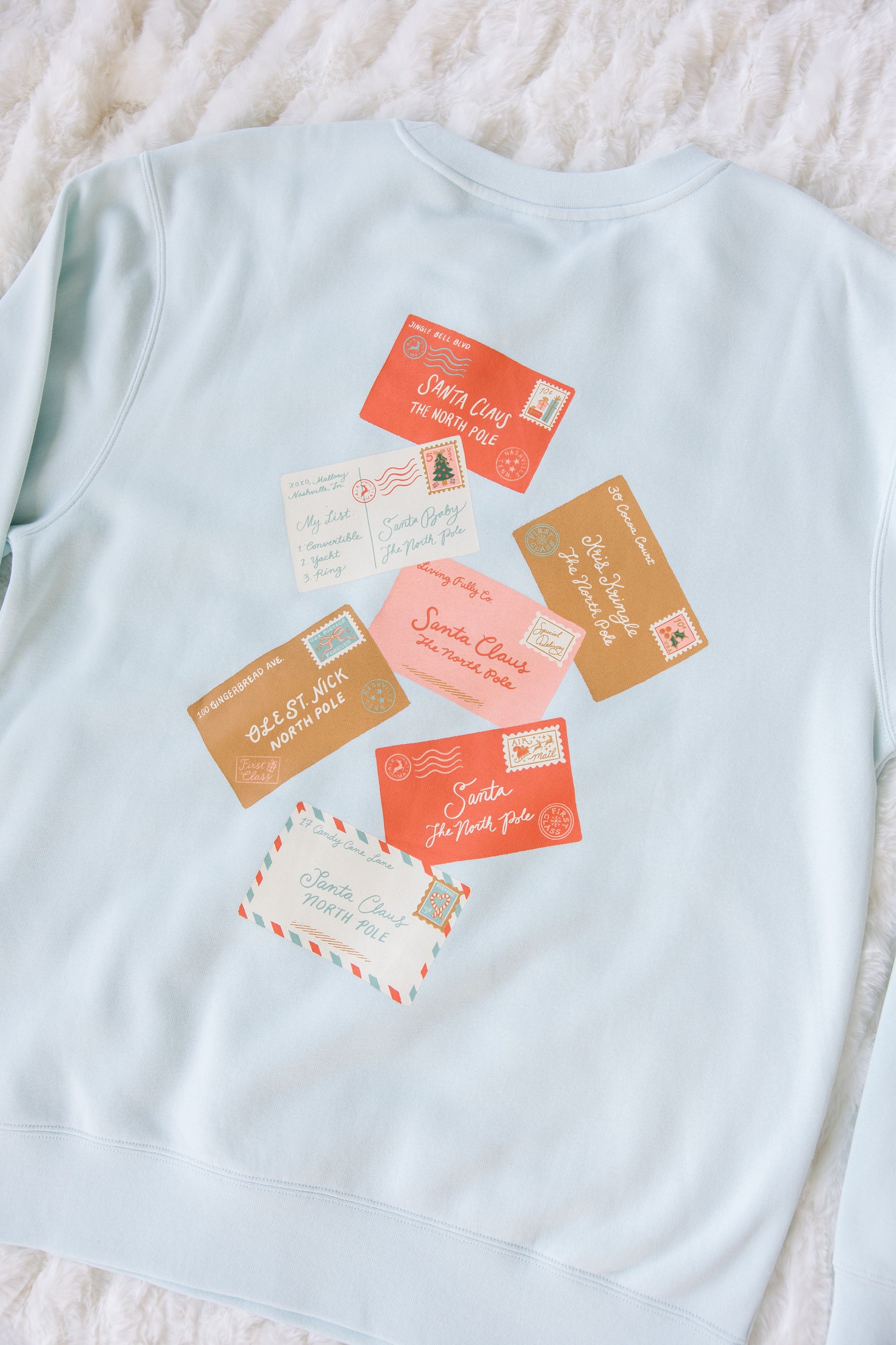 Light blue sweatshirt with vintage-style postcards graphic on a textured surface
