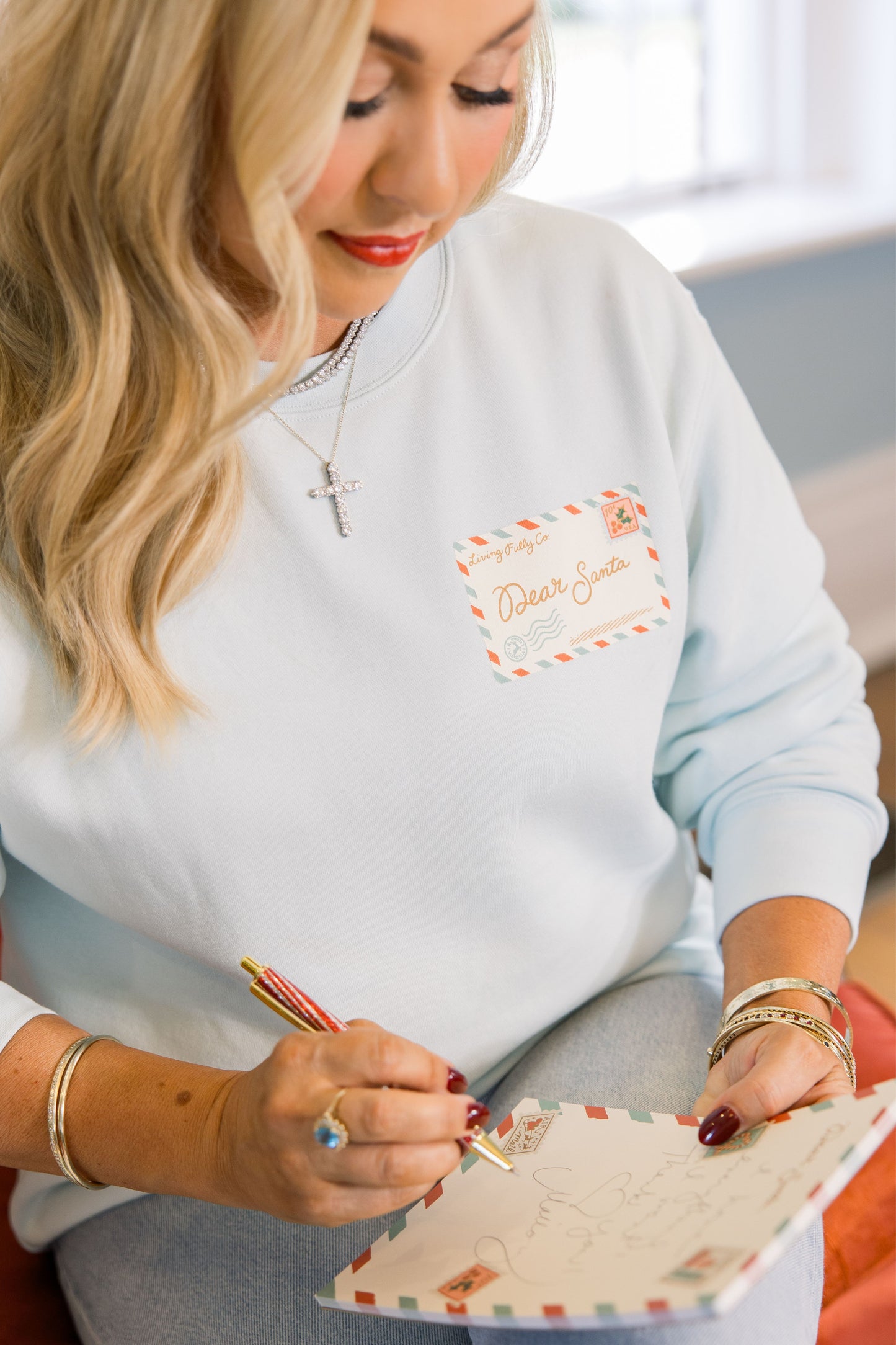 Woman wearing a light blue sweatshirt with a logo, writing on a notepad.