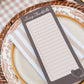 A rectangular 'Living Thankfully' gratitude card with lined writing space, styled on a beige and white striped napkin over a patterned ceramic plate and woven placemat.