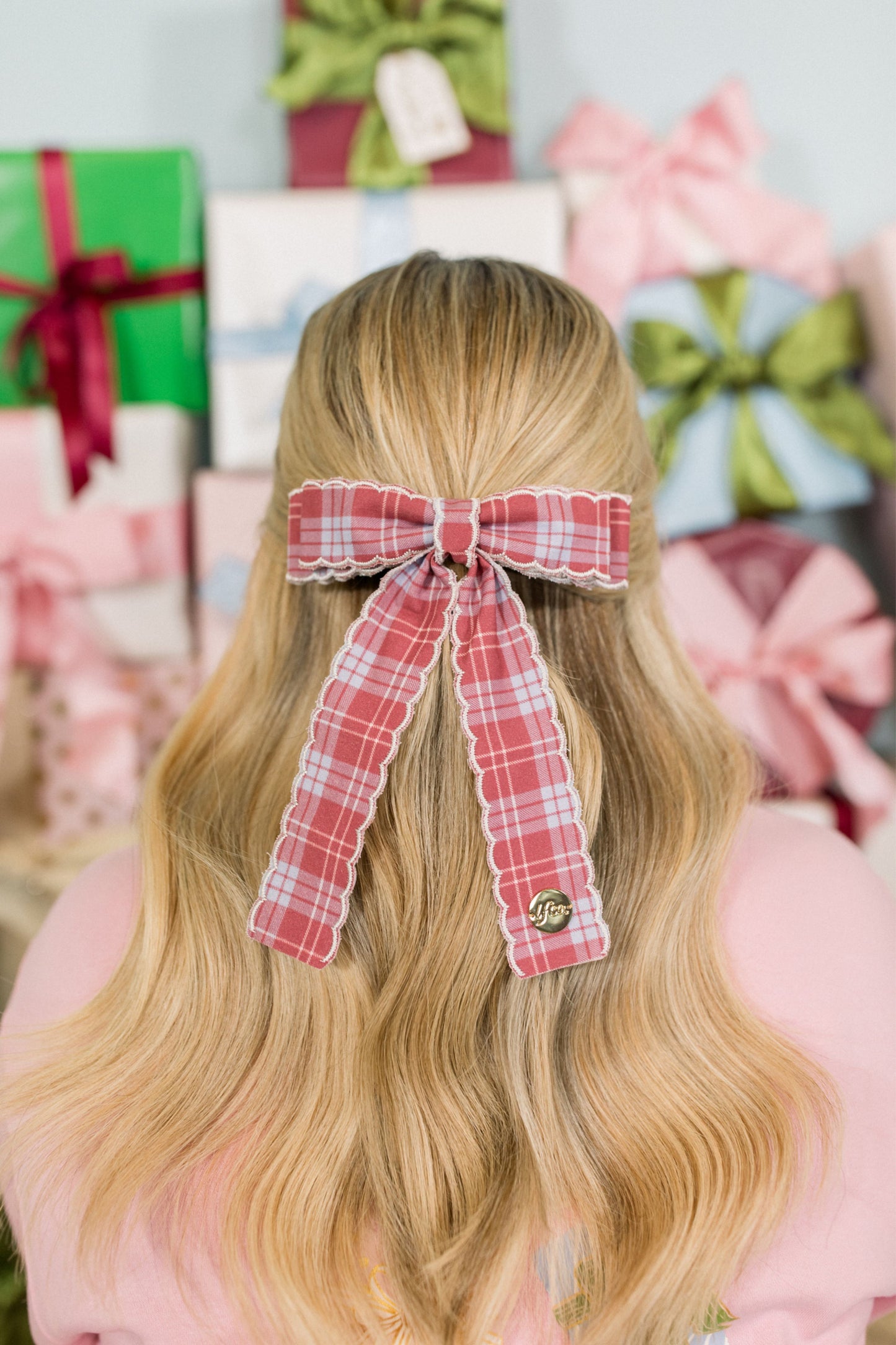 Person with a red plaid hair bow in front of gift boxes
