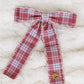 Red and white plaid bow on a textured white background