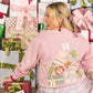 Woman wearing a pink sweater with gift design in front of Christmas presents